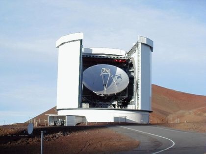 Photo extérieure d'un bâtiment blanc circulaire ouvert sur la façade avec, à l'intérieur, un télescope blanc pointant vers le ciel