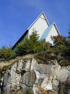 Photo de deux toits coniques blancs au sommet d'une colline rocheuse, cachée par de petits conifères