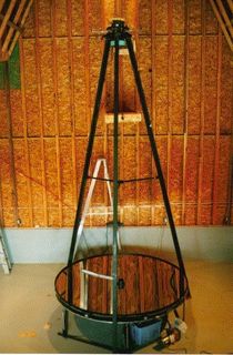 Photo of a black-structured telescope pointing towards the ceiling with a liquid lens located near the floor located in a building with walls of wood