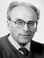 Black and white photo of a man with glasses wearing a shirt, tie and sweater