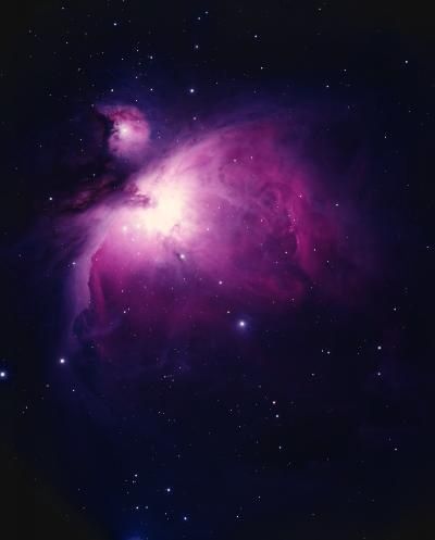 Photographie d'une nébuleuse au centre lumineux et entouré d'un halo aux tons de rose sur un fond noir étoilé