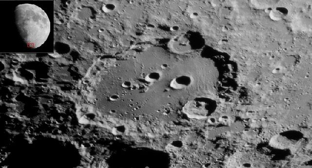 Photographie en noir et blanc d'un cratère lunaire contenant plusieurs petits cratères avec, en mortaise, son emplacement encadré sur une photo de la lune.