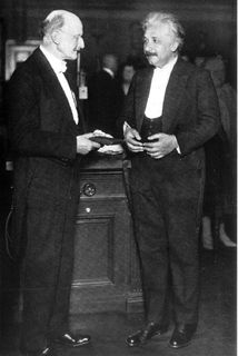 Photo en noir et blanc de deux hommes debout, en habit de soirée et discutant ensemble