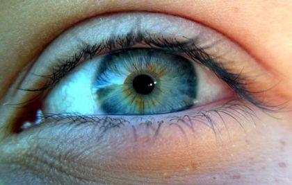 Close-up colour photo of a human eye with a blue iris tinged with yellow and brown.