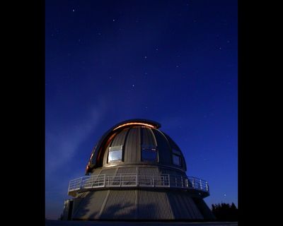 Photo nocturne d'un dôme métallique devant un ciel étoilé