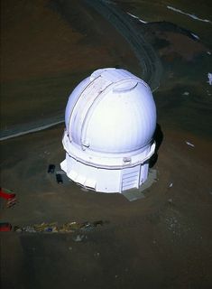 Aerial photo of an observatory with its white dome closed, located on undeveloped land