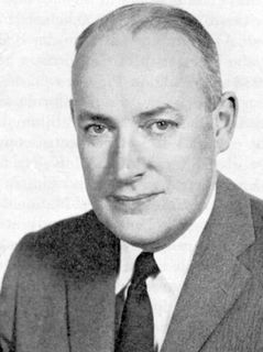 Black and white photo of a man with his hair combed back, wearing a suit and tie