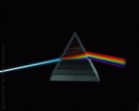 Image of a beam of light passing through a transparent pyramid-shaped prism and the separation of light on the other side, against a very black background