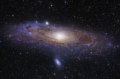 Photo d'un point lumineux central, entouré de points lumineux dispersés et d'anneaux aux teintes mauves formant un large disque concentrique dans un ciel étoilé au fond noir